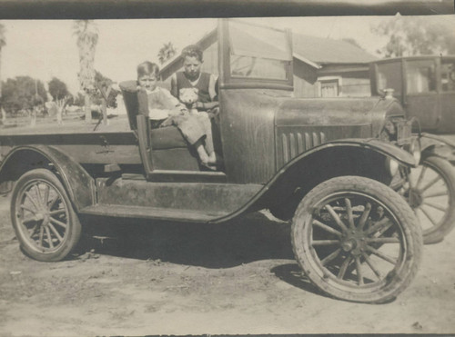 Robert and James McNeil posing in old automobile in Huntington Beach, ca. 1935