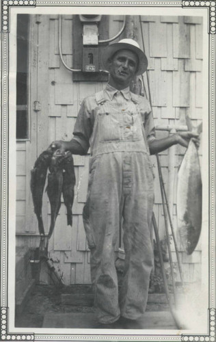 Sam Hennig holding fish in Huntington Beach, 1940