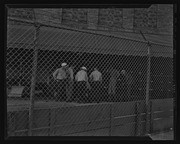 Men standing behind fence during ILWU Sears Strike, California Labor School