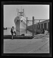 Man in front of ship at dock, California Labor School