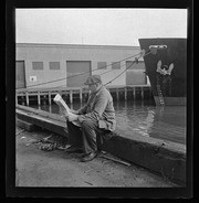 Man reading newspaper on watefront dock, California Labor School