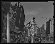 Man wearing sign walking on stilts past Hotel Shaw, San Francisco, Calif., California Labor School