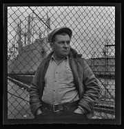 Man standing on dock in front of chain-link fence, California Labor School