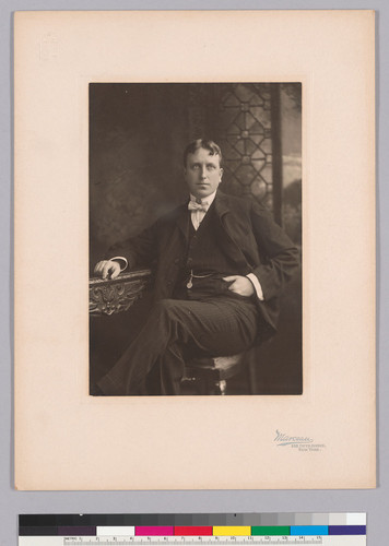 Portrait of William Randolph Hearst, Sr. seated at table, with left hand in pocket