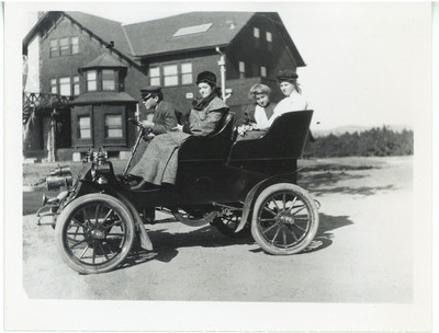 3 women with Stanley Chapman at the wheel of the family's first automobile, a 1902 one-cylinder Cadillac