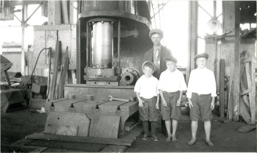 Ralph Buss (brother of Helen Buss) and his three sons (L to R) Ernest, Claude, and Charley standing in front of hydraulic press at the Southwestern Shipyards, San Pedro, California