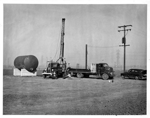 Worker and trucks near oil drill