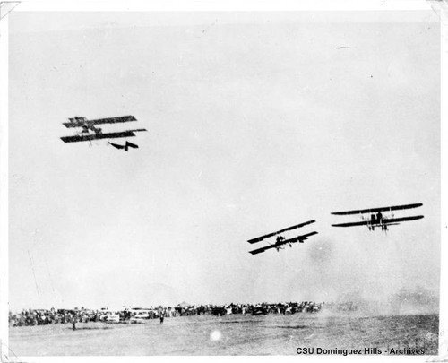 Three planes flying over track and spectators