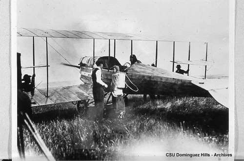 Parachute jumper preparing to climb into biplane