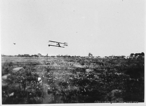 Curtiss biplane in flight over field