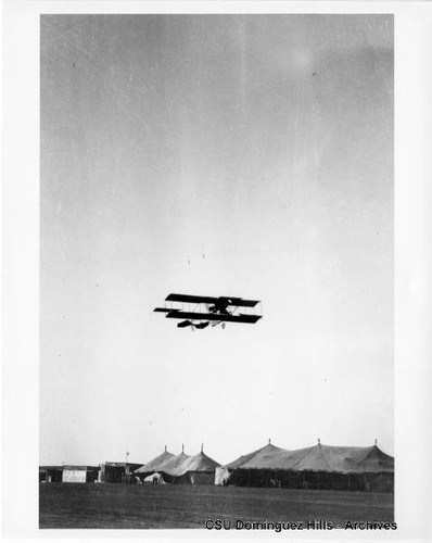 Curtiss Biplane in flight over tents (1)