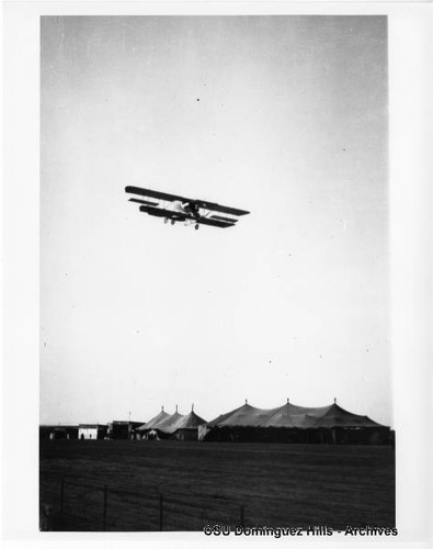 Aviator Martin in Martin Curtiss-type biplane in flight over tents (2)