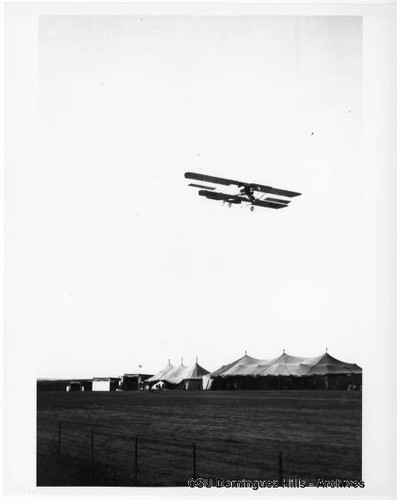 Aviator Martin in Martin Curtiss-type biplane in flight over tents (3)