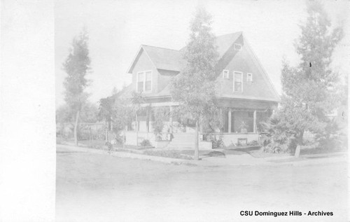 Black house with grown trees and sidewalk