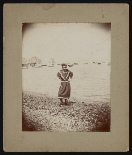 Woman in old-fashioned swimsuit by ocean, front of photograph