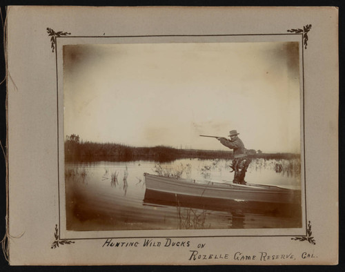 Hunter in boat aims rifle