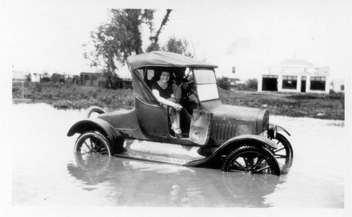 Young woman in car stuck in flooded street