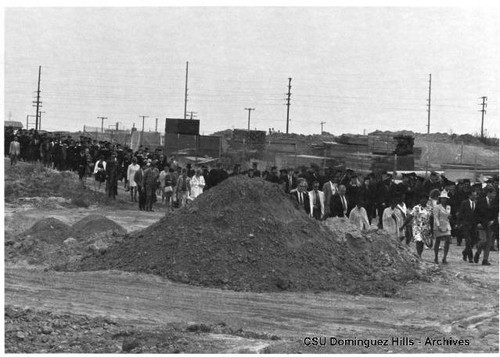 Family members walk on dirt road to graduation