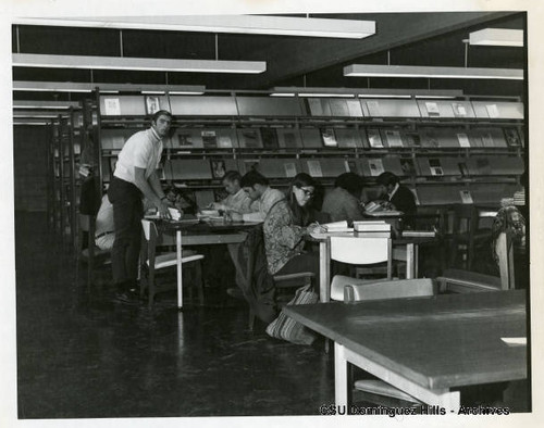 Students study at tables near periodicals rack in Small College Library