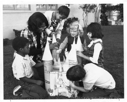 Children building castle with teacher