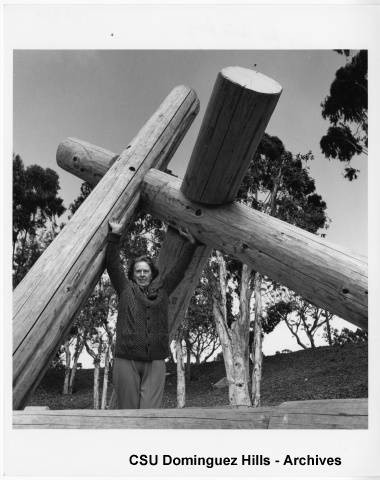 Claire Falkenstein standing under sculpture timbers