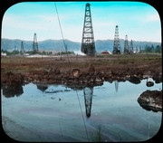 Colorized view of lake pit with oil derricks beyond. (4557)