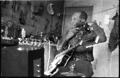 Blues musician Jesse Fuller preparing to play the fodella in his basement