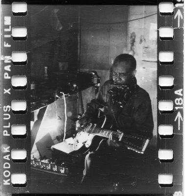 Blues musician Jesse Fuller playing the fodella in his basement