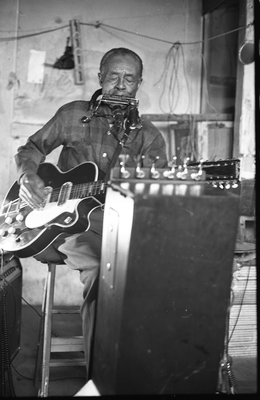 Blues musician Jesse Fuller playing the fodella in his basement