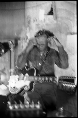 Blues musician Jesse Fuller preparing to play the fodella in his basement