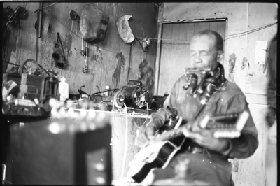 Blues musician Jesse Fuller playing the fodella in his basement