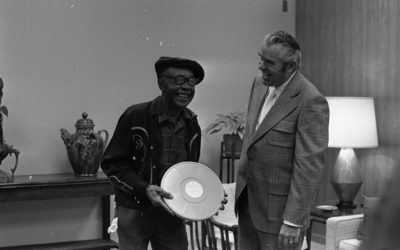 Former museum director John Peetz (left) presenting Jesse Fuller with film "Jesse Fuller: Portrait" during concert at the Oakland Museum