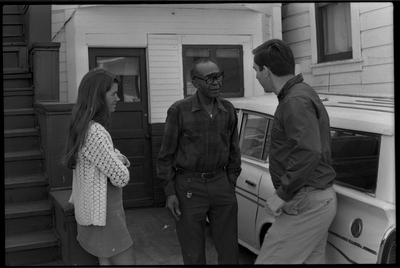 Jesse Fuller speaking with man and woman in front of his home in West Oakland