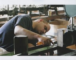 Russell Strickland with a screwdriver in hand checking a machine, Sunset Line & Twine Company in Petaluma, California, Dec. 5, 2006