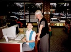 Patti Lewis helping a boy at a computer