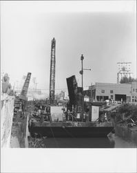 Pile driver on a barge working on the Washington Street Bridge replacement, Petaluma, California, 1968, viewed from Water Street