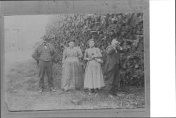 Four people in front of a stack of logs