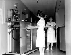 Removing food trays from warming units at Santa Rosa General Hospital, Santa Rosa, California, 1962