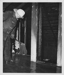 Petaluma Fire Department firefighter mopping up water at the scene of an unidentified fire in Petaluma, California, 1950s or 1960s