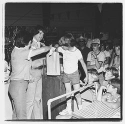 Bank of Marin representative offering a prize to a raffle ticket winner in the Bank of Marin booth at the Sonoma-Marin Fair, Petaluma, California, 1978