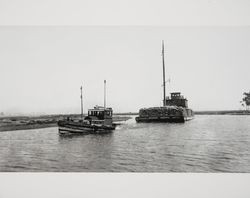 Tug boat pulling a barge on the Petaluma River, Petaluma, California, 1920s