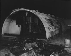 Petaluma Fire Department firefighters inside a burned Quonset hut, 1950s