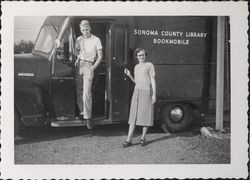 Louis Schultz stepping out of the bookmobile while Mildred Edmundson looks on