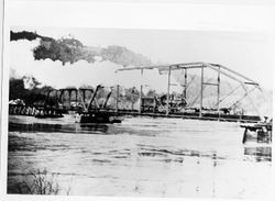 Unidentified locomotive pushing a car across a Russian River bridge