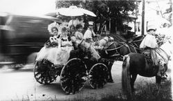 Unidentified teenage girls in a buggy of marigolds and ferns for a Rose Parade