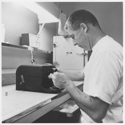 Unidentified worker operating test equipment, possibly at Optical ...