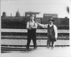 Two unidentified men beside a freight train