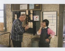 Harold Allen and Mae Tam laughing by the punch time clock, Sunset Line & Twine, Petaluma, California, Dec. 2006