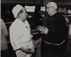 Fr. Boeddeker speaking to kitchen worker, 121 Golden Gate Avenue, San Francisco, California, February 1979