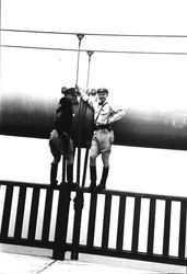 Irv Rohner and Ira Hein, state highway patrolmen, standing on the railing of the Golden Gate Bridge, May 26, 1937, 1937